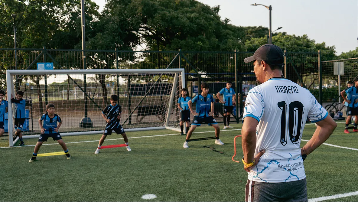 Entrenador observando a sus jugadores durante un ejercicio