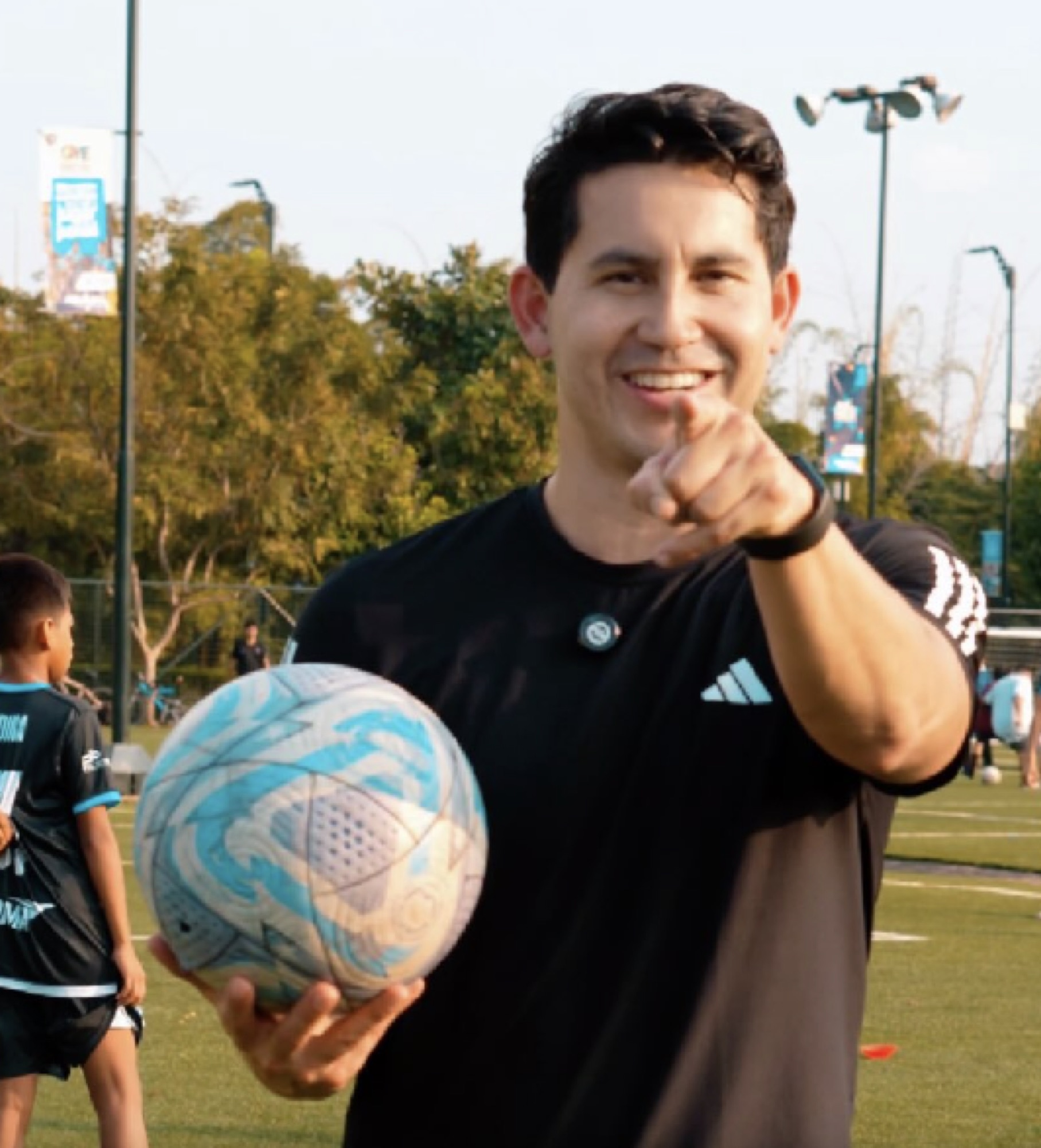 Xavier Estrada, fundador de UNQA, sonriendo con un balón en la cancha