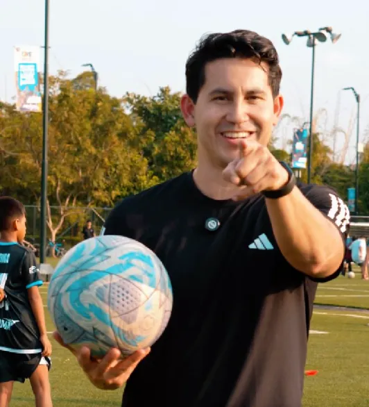 Xavier Estrada, fundador de UNQA, sonriendo con un balón en la cancha