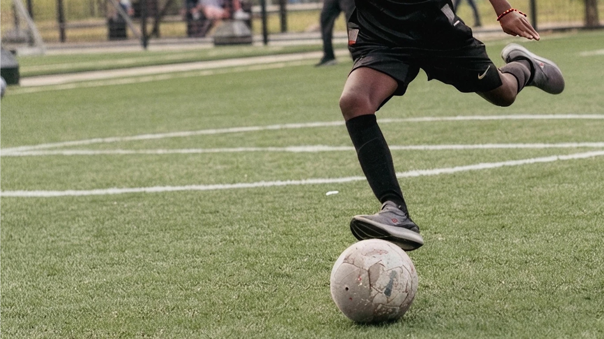 Joven futbolista golpeando el balón en la cancha